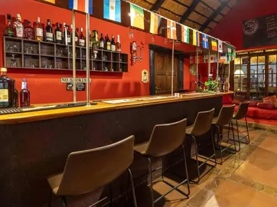 a bar with a row of chairs and bottles of alcohol at Royal Bakoena Hamiltonparks Country Lodge in Hazyview
