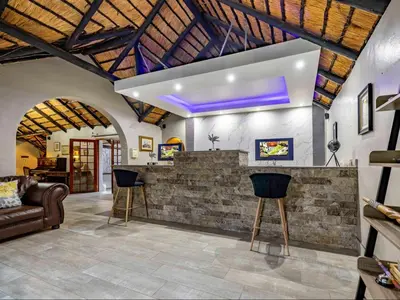 a lobby with a bar with a couch and chairs at Royal Bakoena Hamiltonparks Country Lodge in Hazyview