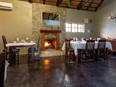 a dining room with tables and a fireplace at Royal Bakoena Hamiltonparks Country Lodge in Hazyview