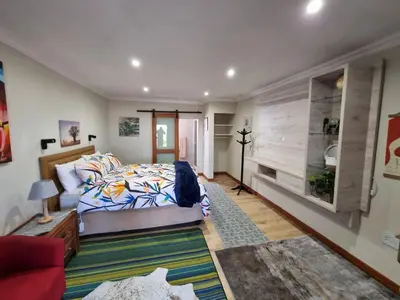 a bedroom with a bed and a living room at Valley View dullstroom - check in at The Highlander Hotel in Dullstroom