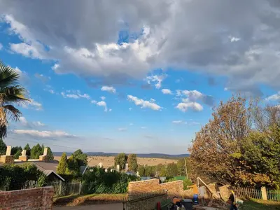 a cloudy blue sky with people walking down a street at Valley View dullstroom - check in at The Highlander Hotel in Dullstroom