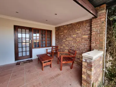 a patio with wooden chairs and a brick wall at Valley View dullstroom - check in at The Highlander Hotel in Dullstroom