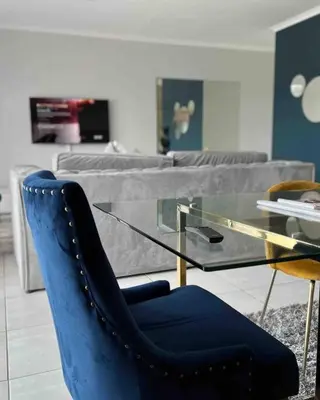a blue chair and a glass table in a room at Luxury Penthouse Apartment at the Blyde Pretoria in Pretoria