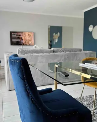 a blue chair and a glass table in a living room at Luxury Penthouse Apartment at the Blyde Pretoria in Pretoria