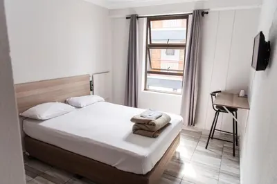 a small bedroom with a bed and a window at Ecomotel Kempton Park in Kempton Park