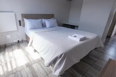a bedroom with a large bed with white sheets at Ecomotel Kempton Park in Kempton Park
