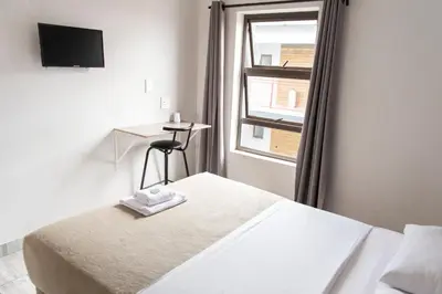 a bedroom with a bed and a desk and a window at Ecomotel Kempton Park in Kempton Park