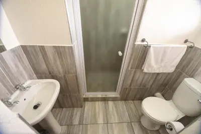 a bathroom with a toilet and a sink and a shower at Ecomotel Kempton Park in Kempton Park
