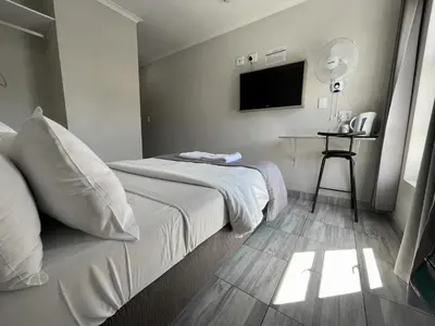 a hotel room with a bed and a television at Ecomotel Kempton Park in Kempton Park