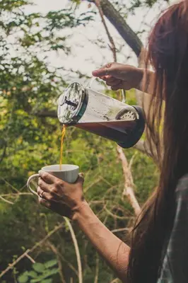 a woman pouring a cup of coffee from a coffeeaffle at Thulamela Couples Retreat in Hazyview