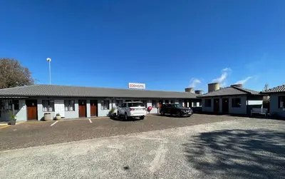 a building with two cars parked in a parking lot at Ecomotel Isando in Kempton Park