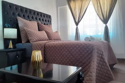 a bedroom with a pink bed with a table and a window at Queens Palace in Pretoria