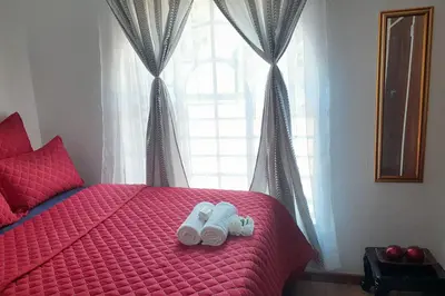 two towels on a red bed in front of a window at Queens Palace in Pretoria