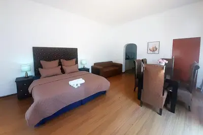 a bedroom with a large bed and a chair at Queens Palace in Pretoria