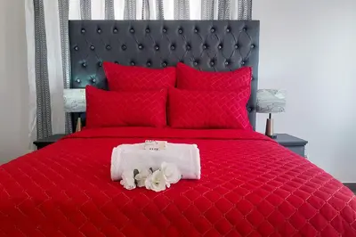 a red bed with red pillows and a white towel at Queens Palace in Pretoria