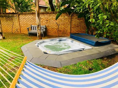a hot tub sitting in the grass next to a bench at Grafiti Boutique Hotel in Bela-Bela
