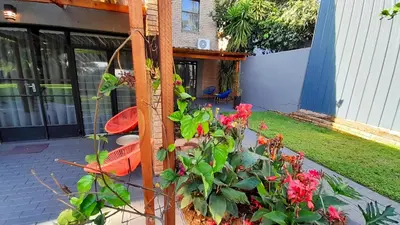a garden with red flowers in front of a house at Grafiti Boutique Hotel in Bela-Bela