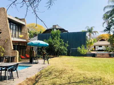 a backyard with a table and chairs and an umbrella at Grafiti Boutique Hotel in Bela-Bela