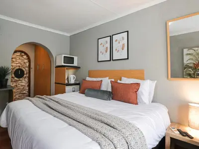 a bedroom with a large white bed with orange pillows at 16 Vaalrivier in Secunda