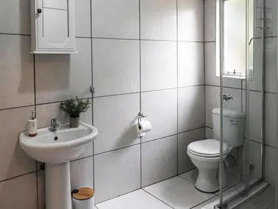 a white bathroom with a toilet and a sink at 16 Vaalrivier in Secunda