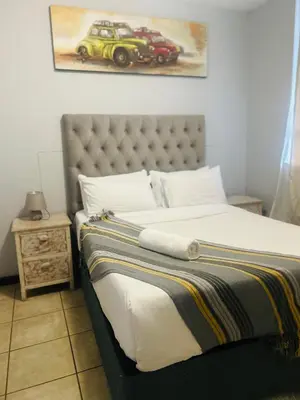 a bedroom with a bed with a car picture on the wall at Menlyn Place Haven in Pretoria