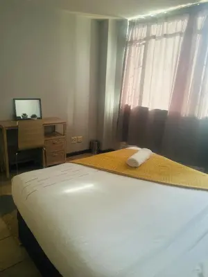 a bedroom with a bed and a desk and a window at Menlyn Place Haven in Pretoria