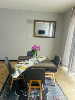 a dining room table with a vase of flowers on it at Menlyn Place Haven in Pretoria