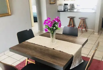 a vase of purple flowers sitting on a wooden table at Menlyn Place Haven in Pretoria