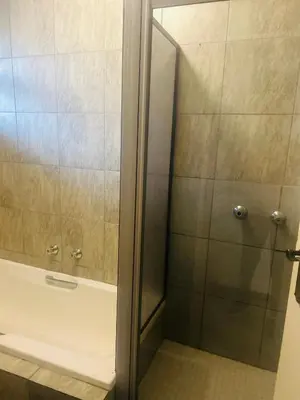 a shower with a glass door next to a bath tub at Menlyn Place Haven in Pretoria