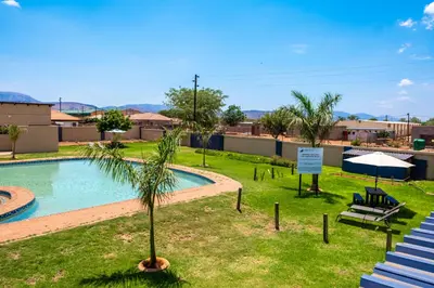 a swimming pool with a palm tree and a sign at Lempitse Lodge in Moletlane