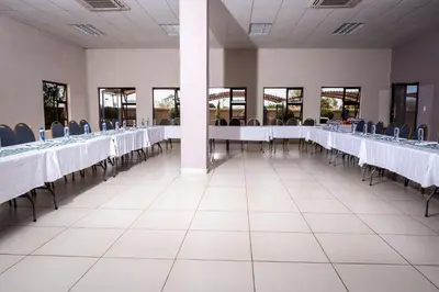 a row of tables in a banquet hall with blue chairs at Lempitse Lodge in Moletlane