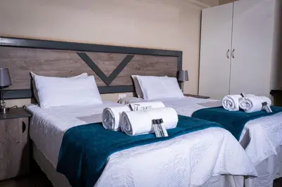 two beds in a hotel room with towels on them at Lempitse Lodge in Moletlane