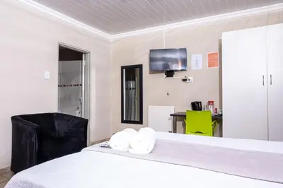 a bedroom with a bed and a tv on the wall at Lempitse Lodge in Moletlane