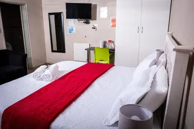 a bedroom with a bed with a red blanket on it at Lempitse Lodge in Moletlane