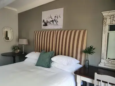 a bedroom with a white bed with a wooden desk at Waterhouse Guest Lodge in Muckleneuk in Pretoria