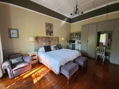 a bedroom with a large bed and two chairs at Waterhouse Guest Lodge in Muckleneuk in Pretoria