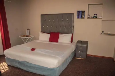 a bedroom with a large bed with a large headboard at Ingwenya Guesthouse in Ermelo