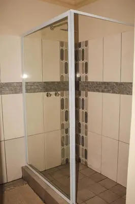 a shower with glass doors in a room at Ingwenya Guesthouse in Ermelo