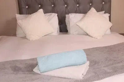 a bed with white pillows and a blue towel on it at Ingwenya Guesthouse in Ermelo