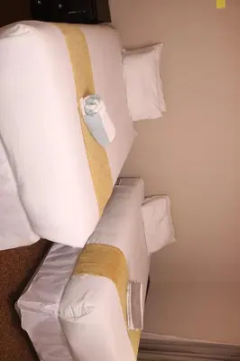 a bed with white sheets and pillows at Ingwenya Guesthouse in Ermelo
