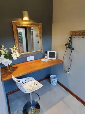 a desk with a mirror and a chair in a room at Bendor Garden Flat in Polokwane