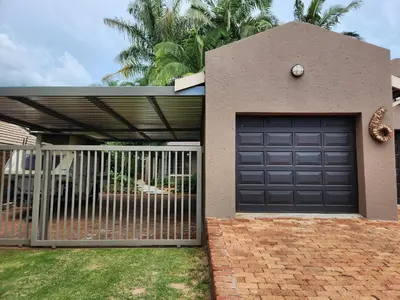 a house with a garage door and a fence at Bendor Garden Flat in Polokwane