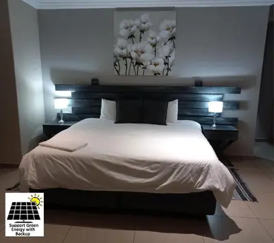 a bedroom with a large white bed with two lamps at SnL Guesthouse at Visarend in Malelane