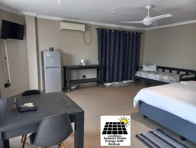 a bedroom with a bed and a desk and a bed and a table at SnL Guesthouse at Visarend in Malelane