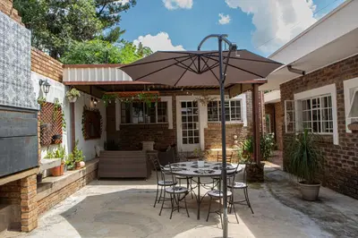 a patio with a table and chairs under an umbrella at Boekenhout Accommodation in Pretoria