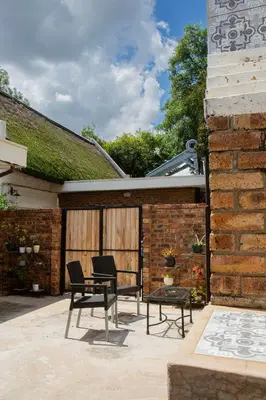 a patio with two chairs and a table and a building at Boekenhout Accommodation in Pretoria