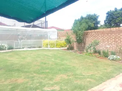 a backyard with a lawn and a brick wall at Bambati residence in Soshanguve