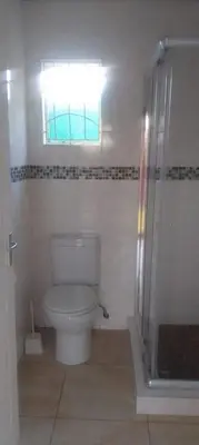 a bathroom with a toilet and a window and a shower at Bambati residence in Soshanguve