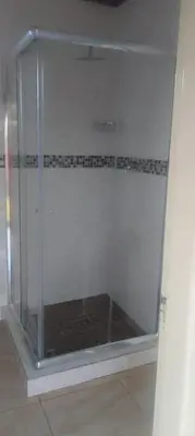 a glass shower in a room with a tile floor at Bambati residence in Soshanguve