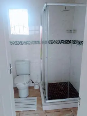 a bathroom with a toilet and a glass shower at Bambati residence in Soshanguve